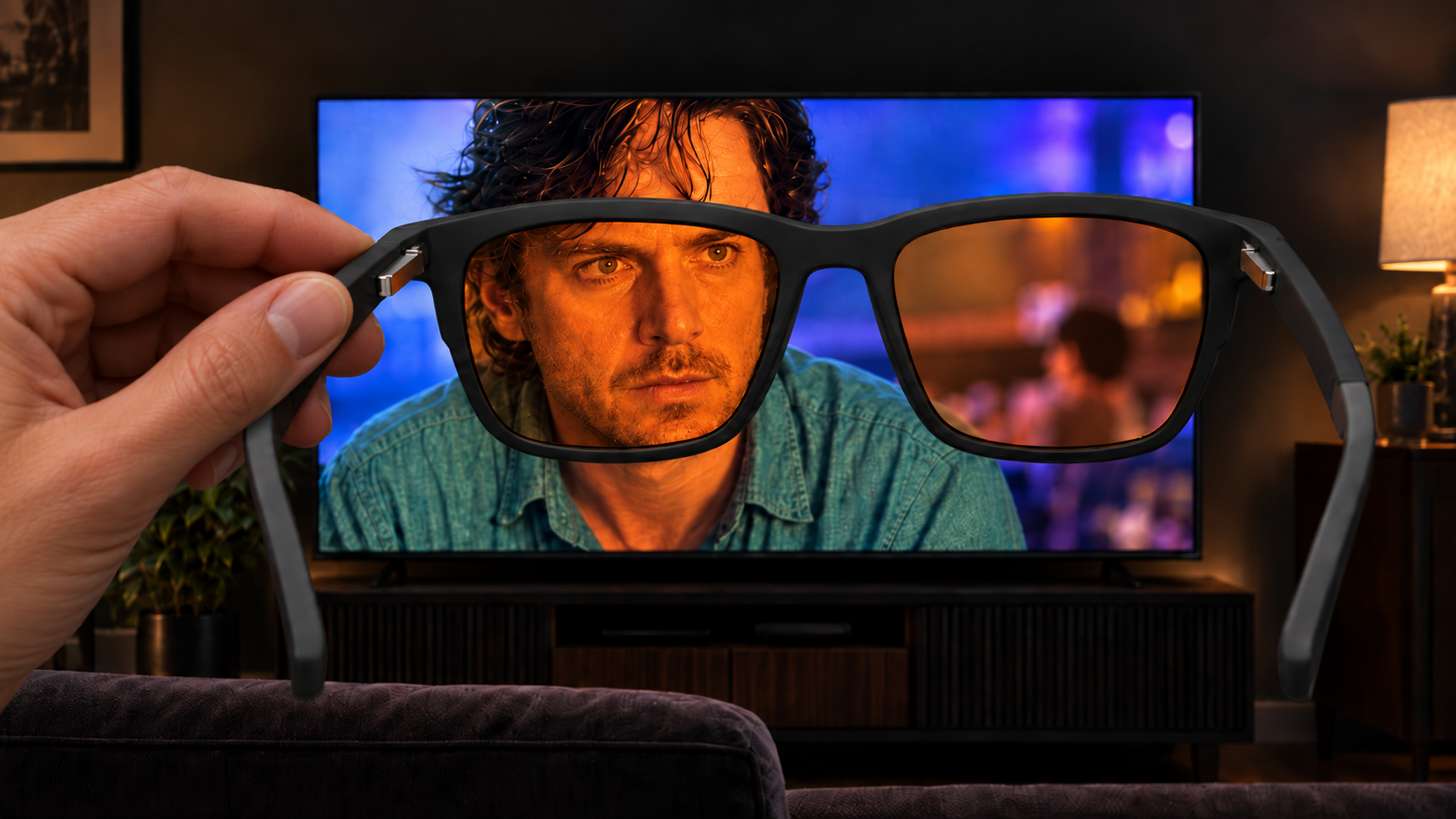 SleepSpec glasses held in front of a television, showing the picture through deep-amber lenses.