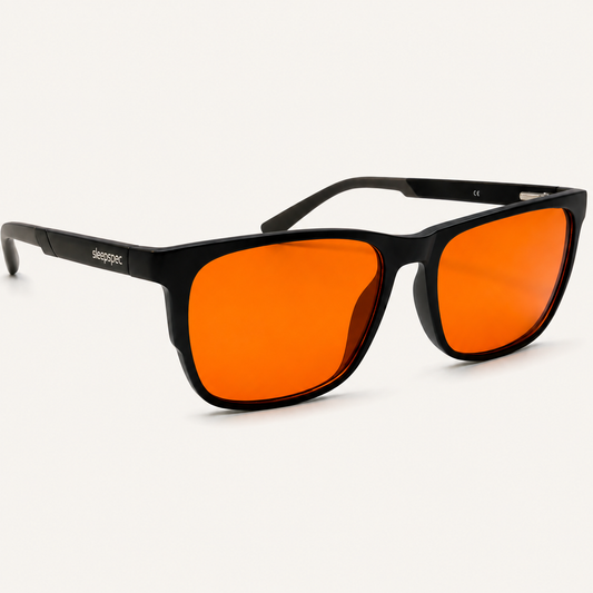 SleepSpec sleep glasses: black frame with deep-amber lenses, angled view on a light background